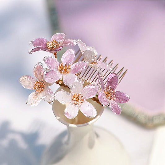 Soft pink blossom accents clustered along dark wooden hair stick, shown upright