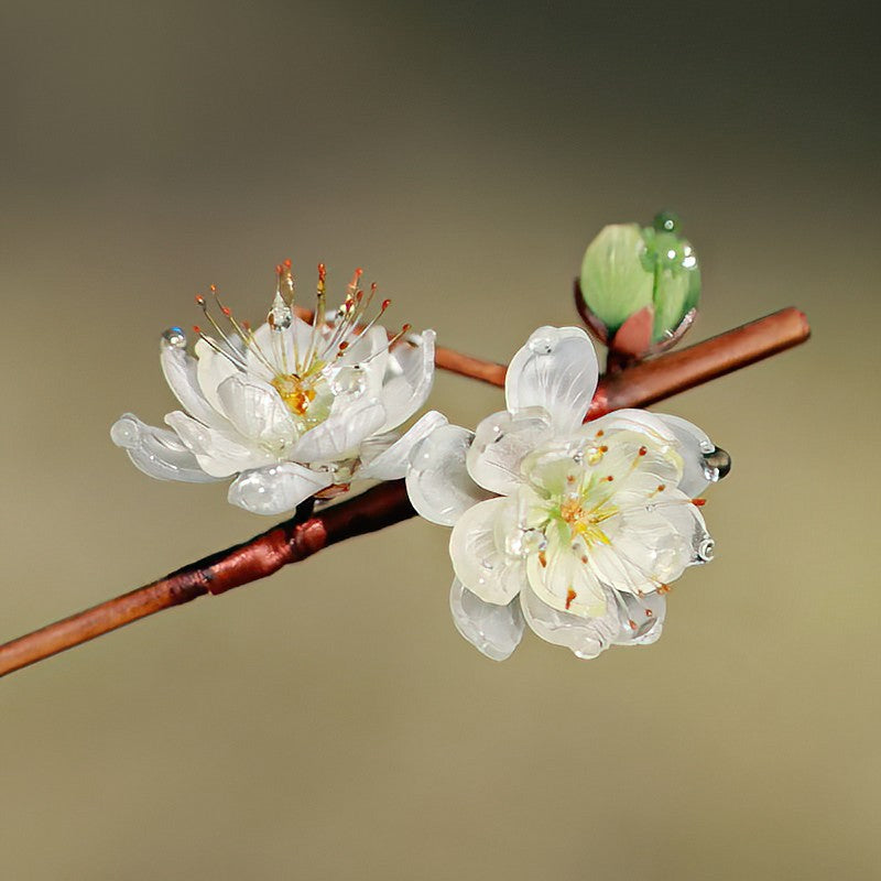 Green blossom hair stick tucked into a low bun, painted floral detail visible