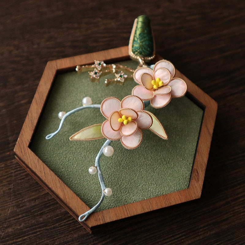 Soft pink layered flower pin with pearled details on cream fabric near lapel