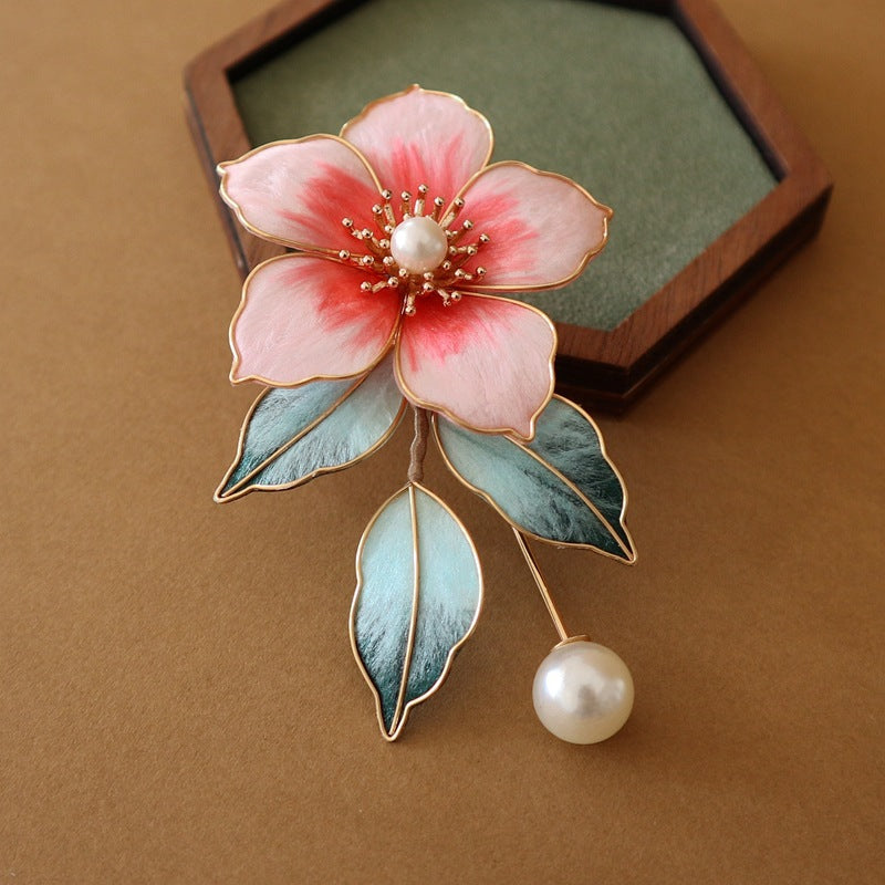 Brooch displayed flat on silk backdrop, soft pink tones and metal pin visible