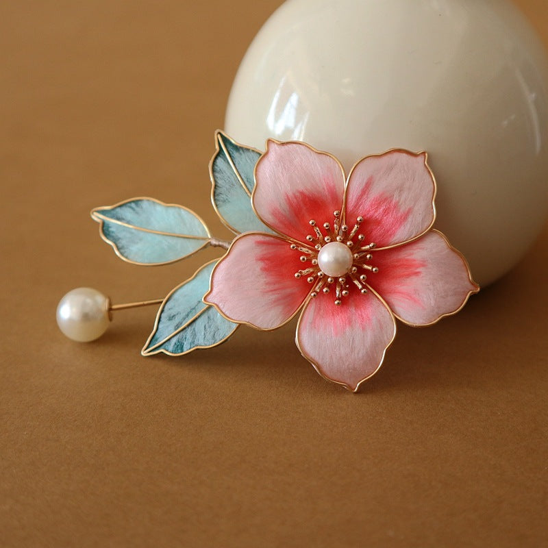 Brooch pinned on pastel fabric showing pink petals, butterfly motif, and bead accents