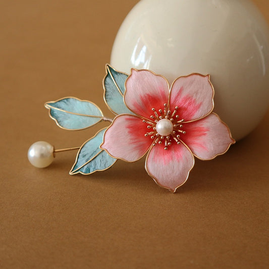 Brooch pinned on pastel fabric showing pink petals, butterfly motif, and bead accents
