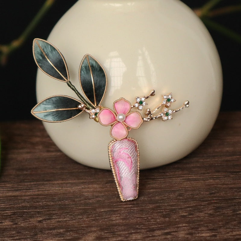 floral vase-inspired brooch pin on a dress viewed close up