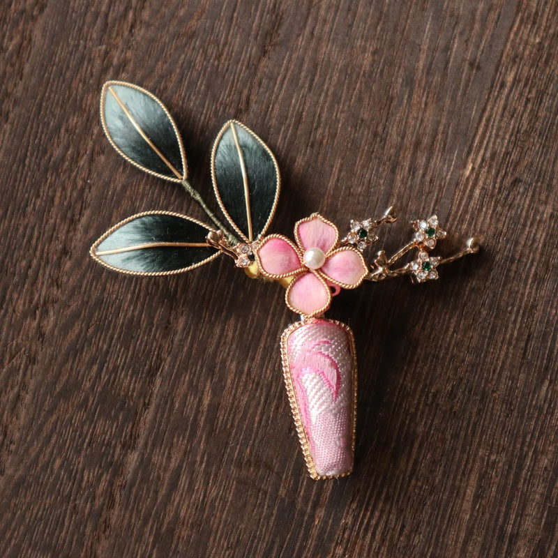 floral vase-inspired brooch pin on a dress displayed on fabric