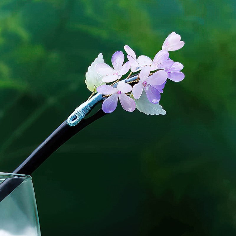 Deep purple floral hair stick pinned through a half-up hairstyle