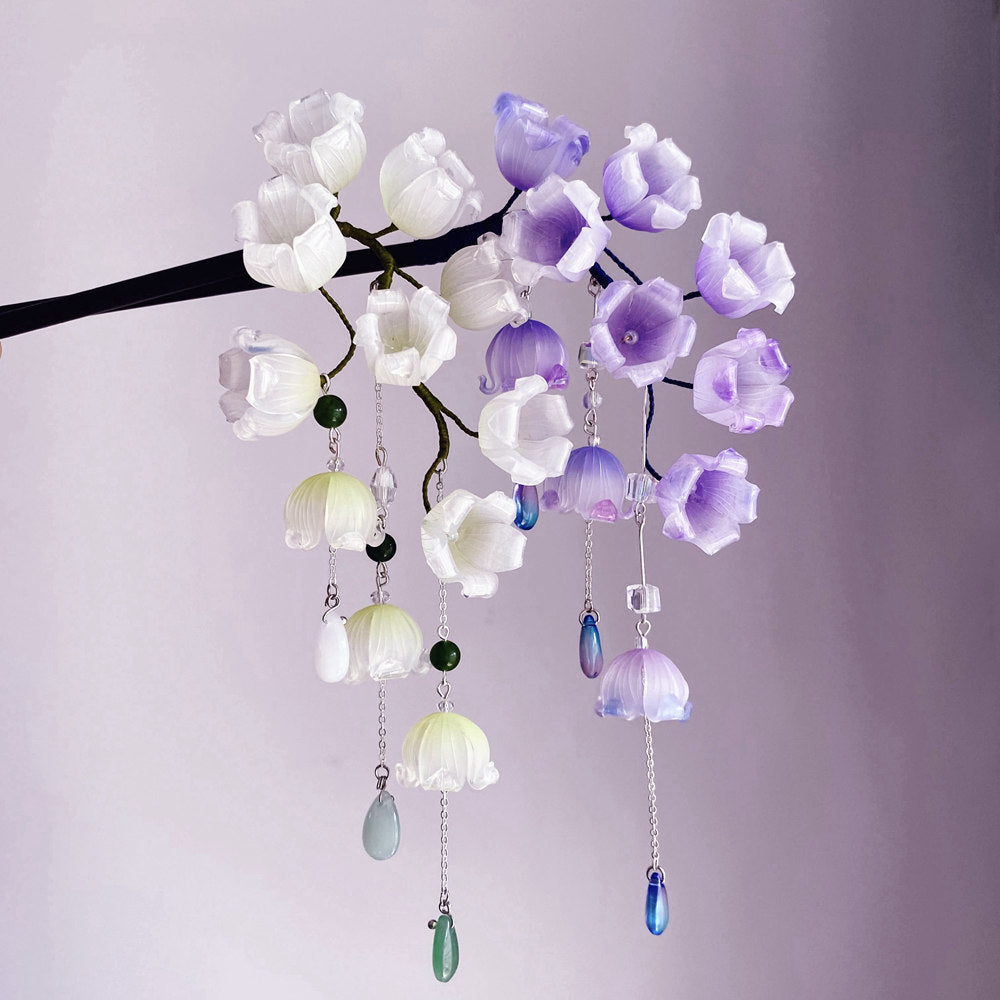 Close-up of purple and white floral ornament with dangling tassel on stick