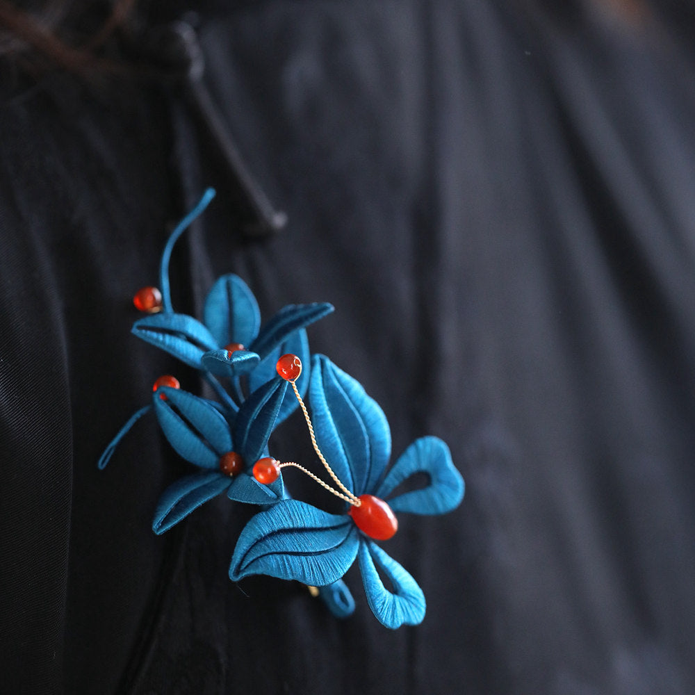 Blue floral brooch pinned on the chest of a fitted qipao dress