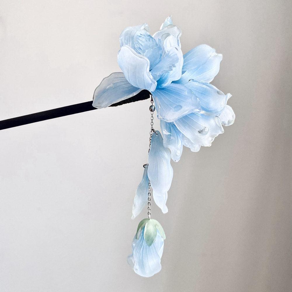 Blue tassel cascading from a slim wooden pin resting through a classic bun