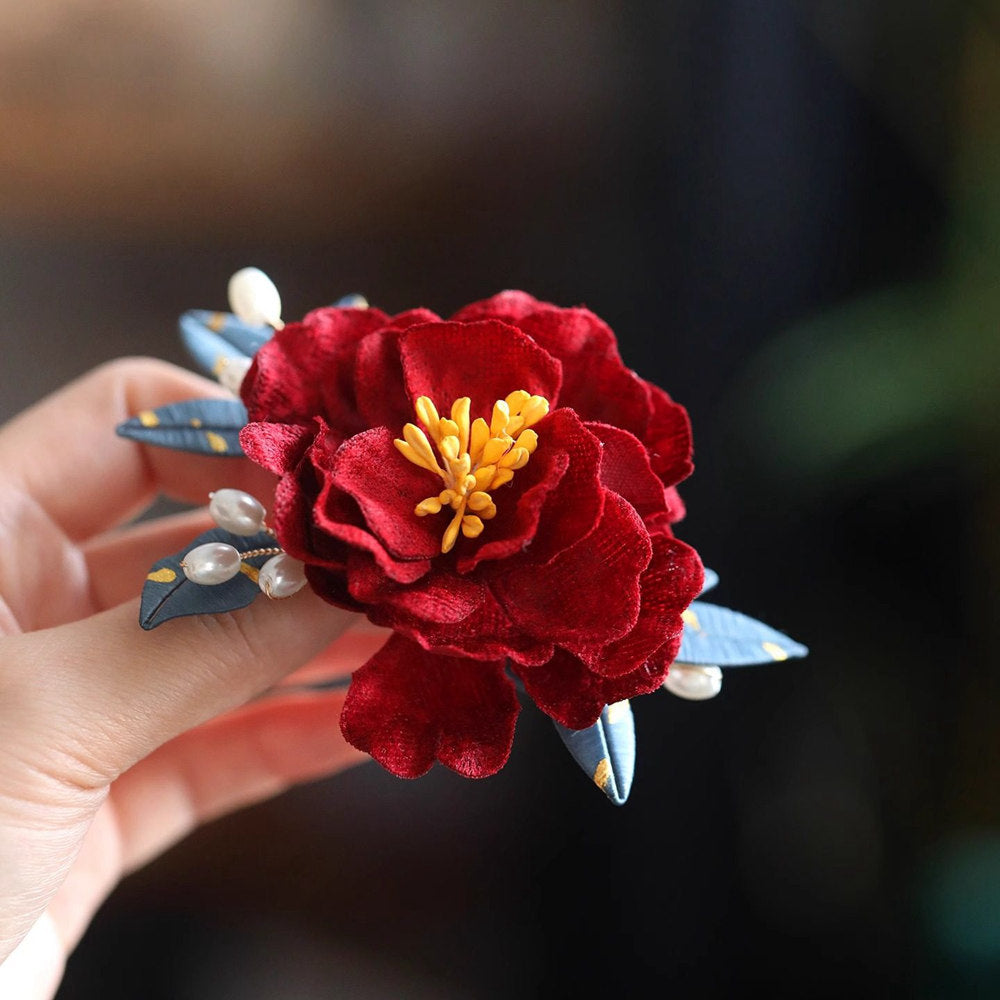 red camellia bridal brooch pin on a dress viewed close up