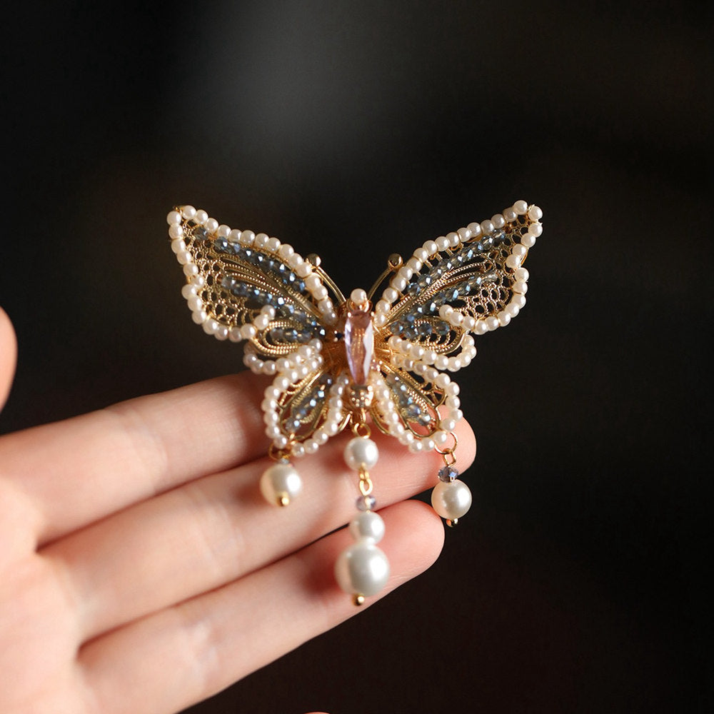 Close-up of butterfly brooch showing pearl detail and textured metal wings