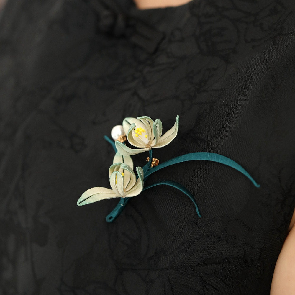Brooch styled on qipao-style outfit at chest, elegant curve and subtle shine