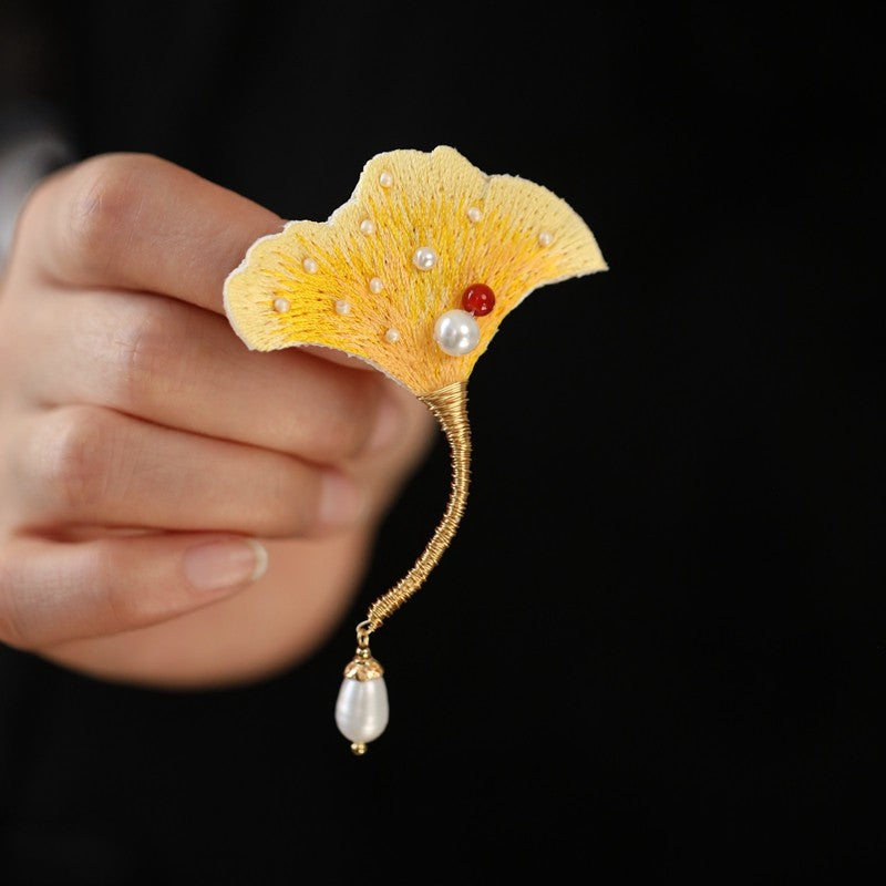 Hand holds brooch showing raised center and textured enamel petal details
