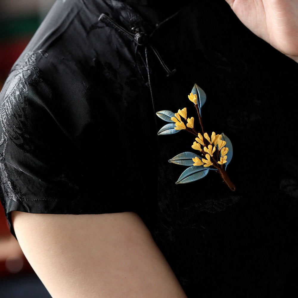 Brooch pinned at Qipao collar with golden petals and ivory pearl-like accents