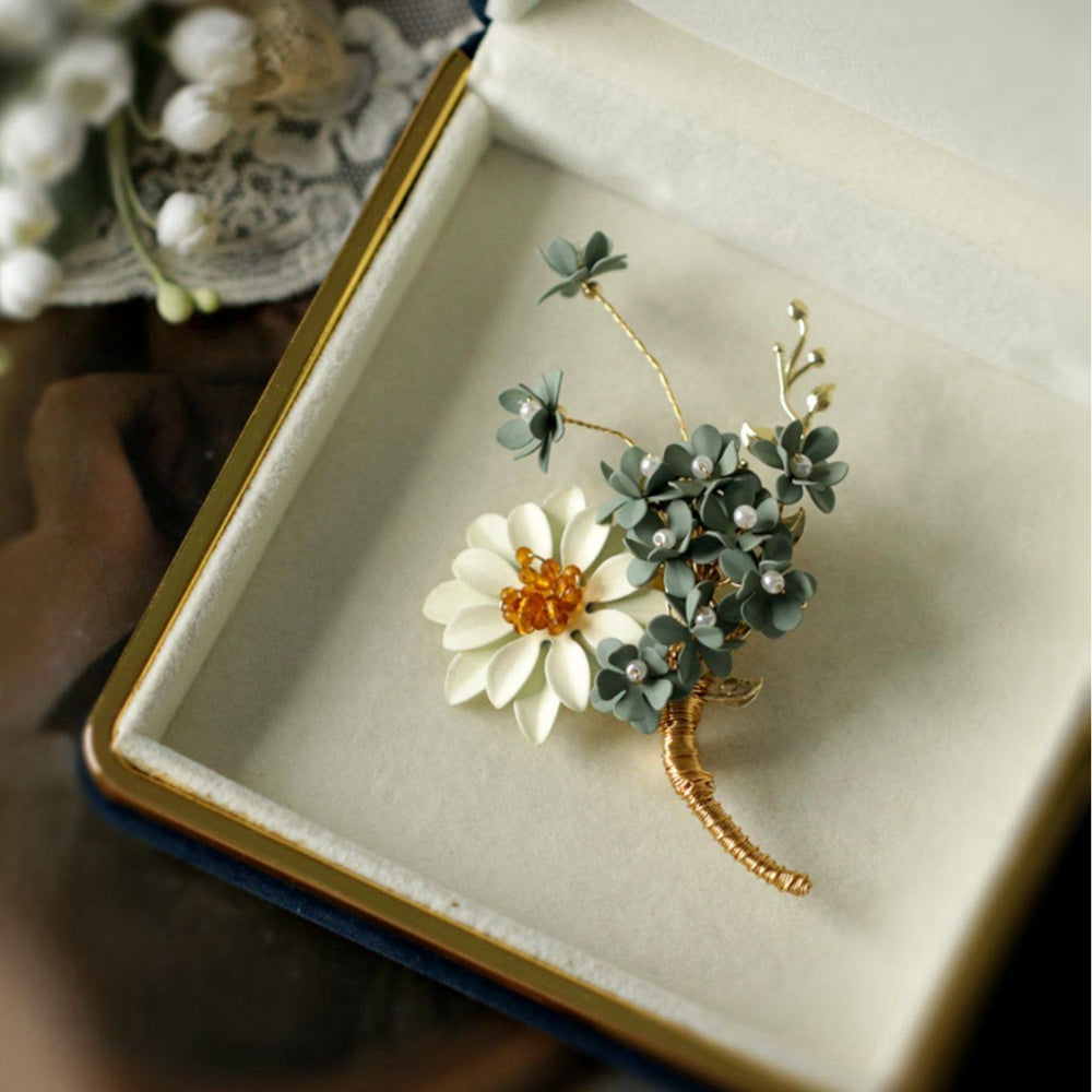 Gold-tone floral brooch presented in cushioned gift box, white fabric backdrop