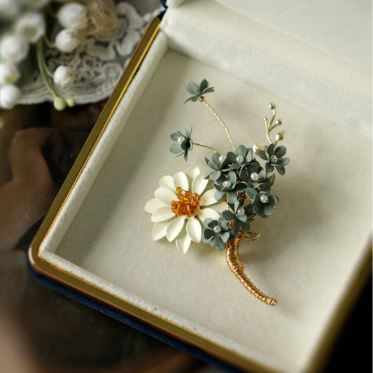 Gold-tone floral brooch presented in cushioned gift box, white fabric backdrop
