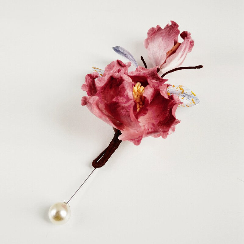pink floral brooch pin with pearl drop on a coat viewed close up