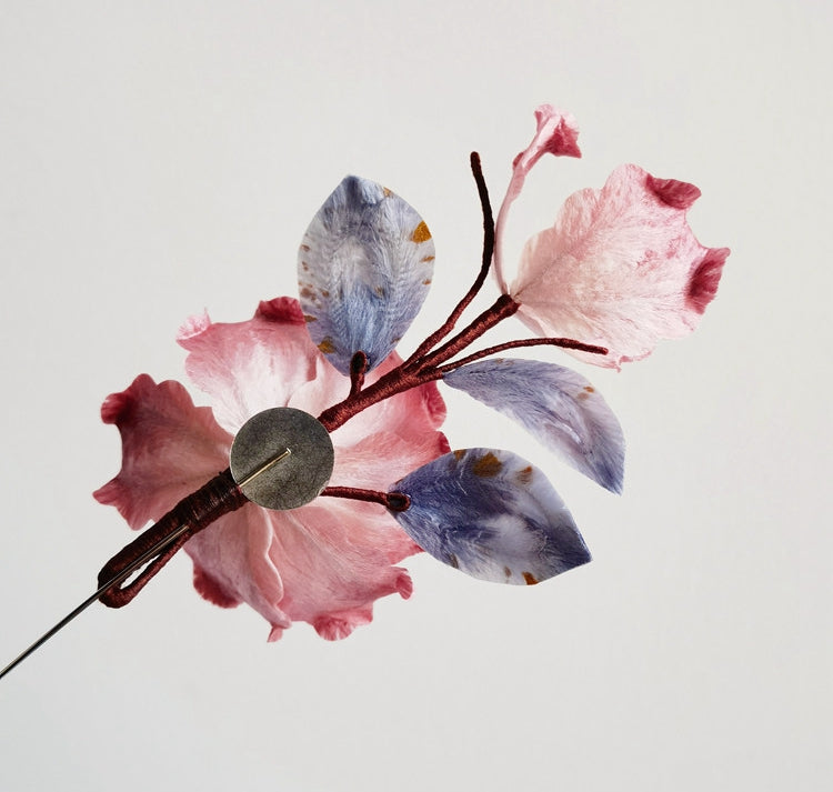 pink floral brooch pin with pearl drop on a coat displayed on fabric