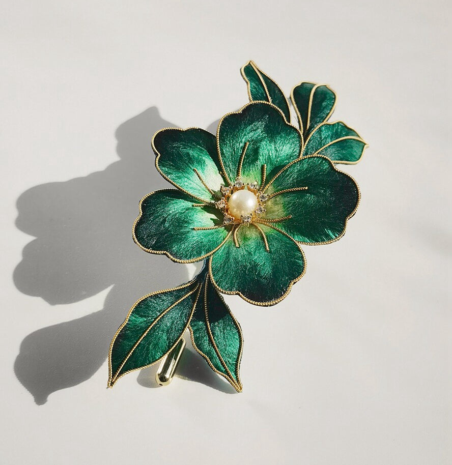 Angled view of a green floral brooch showing layered petals and leaf details on fabric