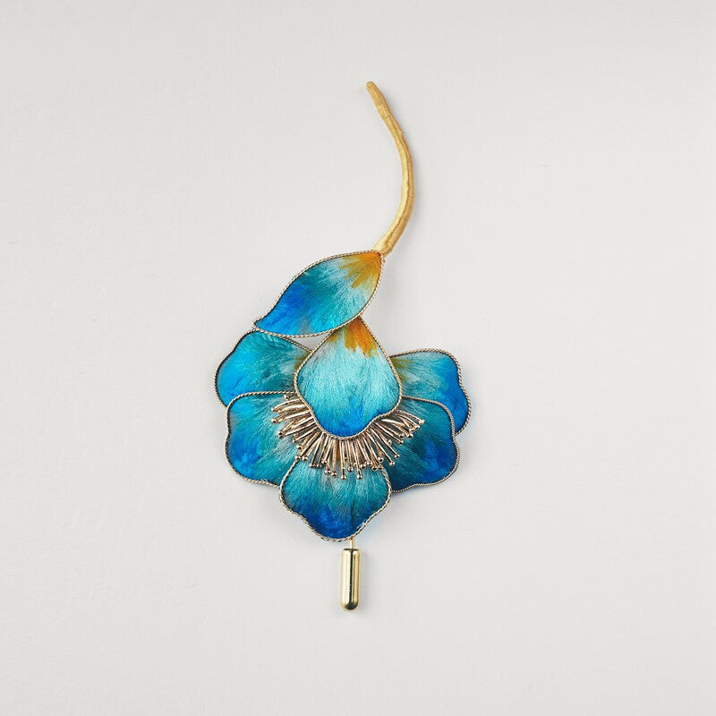 Full floral pin displayed on fabric, blue petals and layered bloom visible