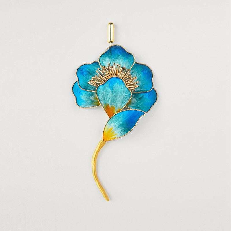 Blue blossom brooch with curved stem pinned to a lapel, angled vertical view