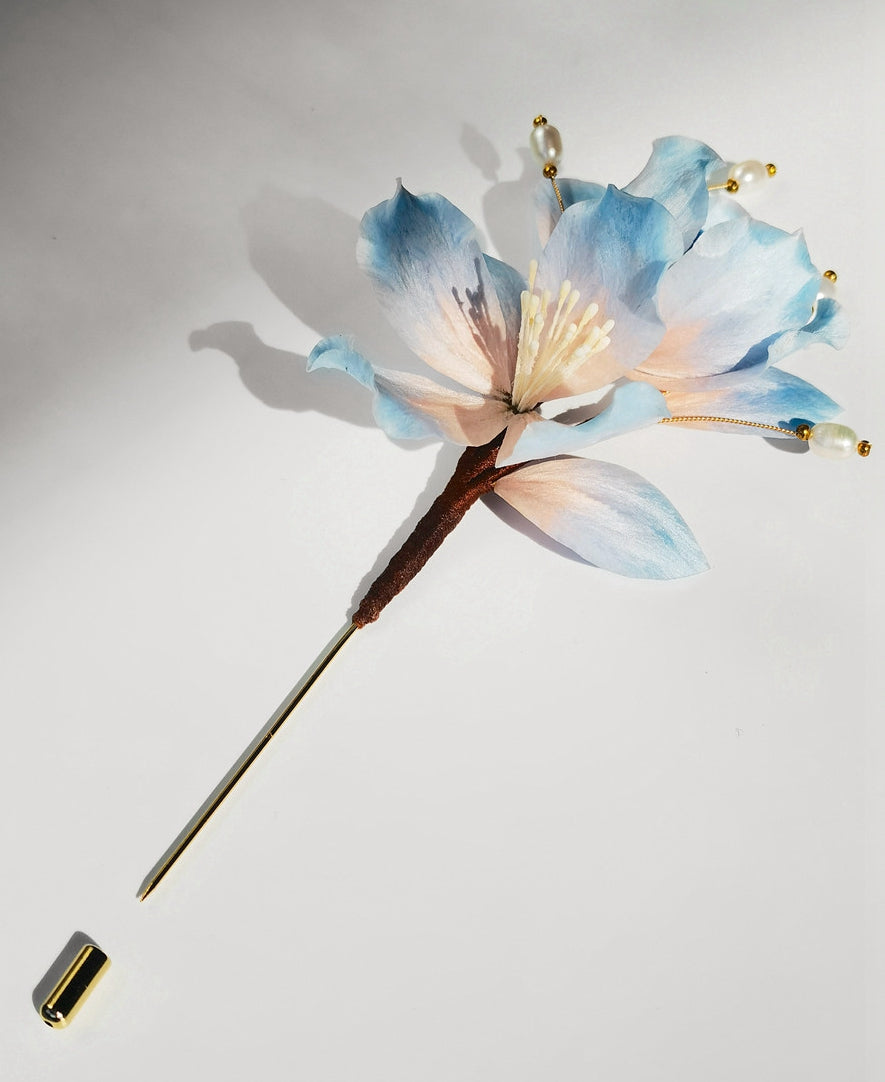 Full-view long-pin brooch in soft blue, ready to fasten on coat