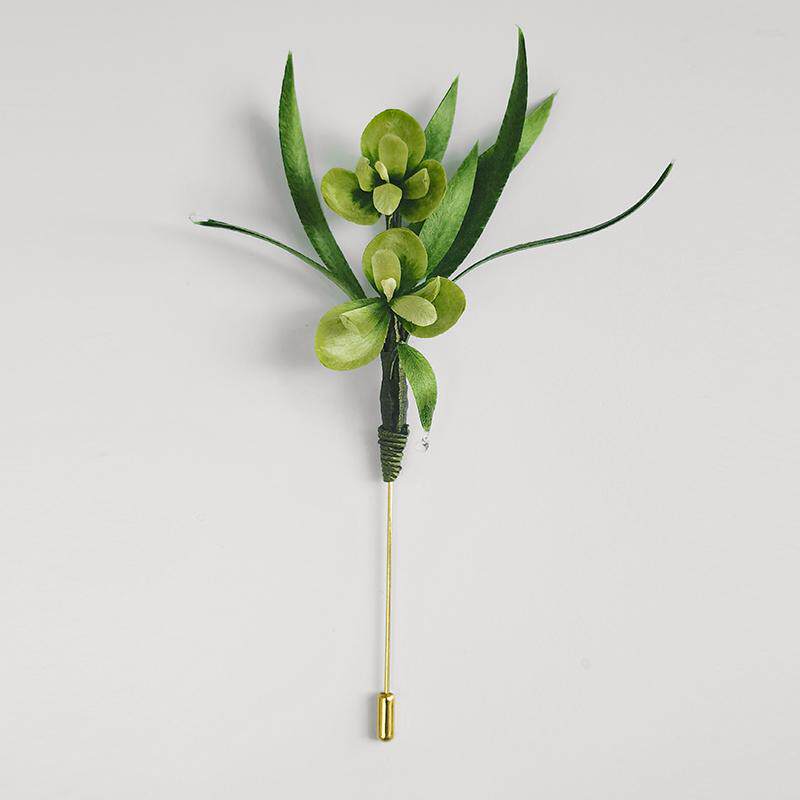Long green brooch with slender stem pinned to dark coat lapel