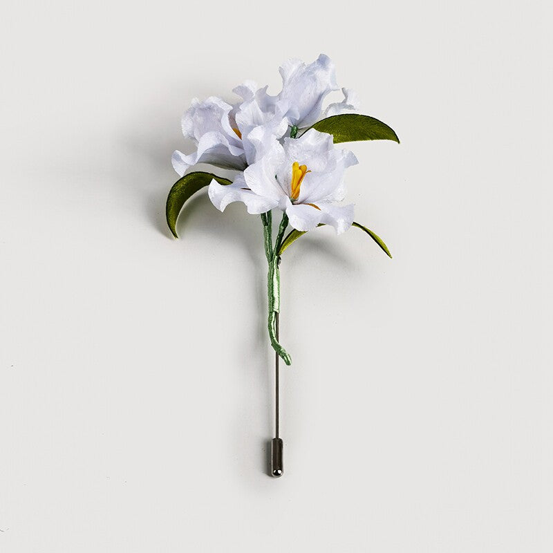 white lily brooch pin on a wedding guest dress viewed close up