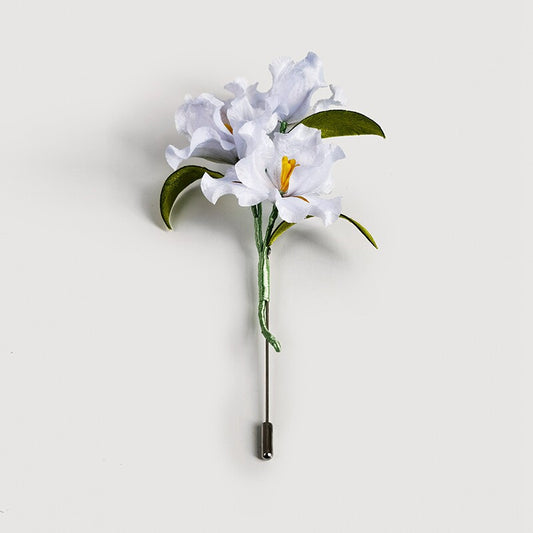 white lily brooch pin on a wedding guest dress viewed close up