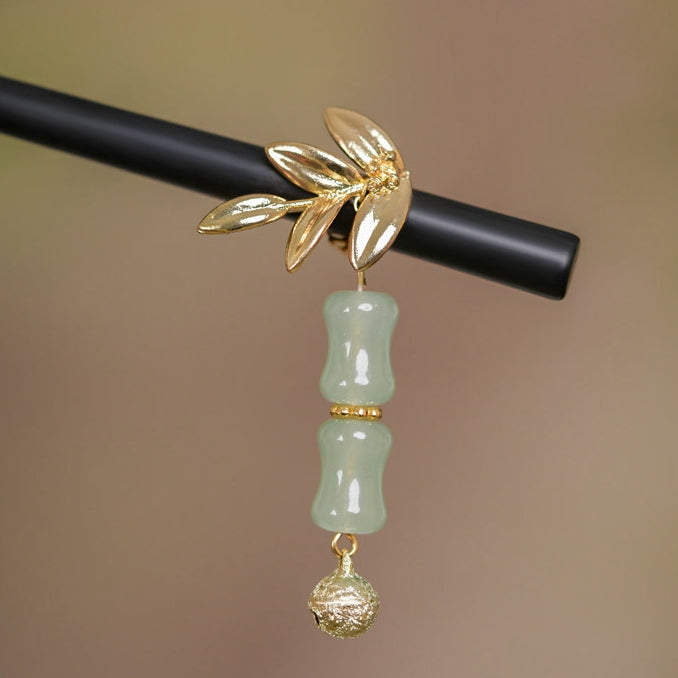 Close-up of green stone-like accent and delicate tassel hanging from the stick