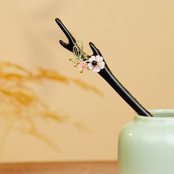 Displayed curved hair stick in black and pink with gold detail