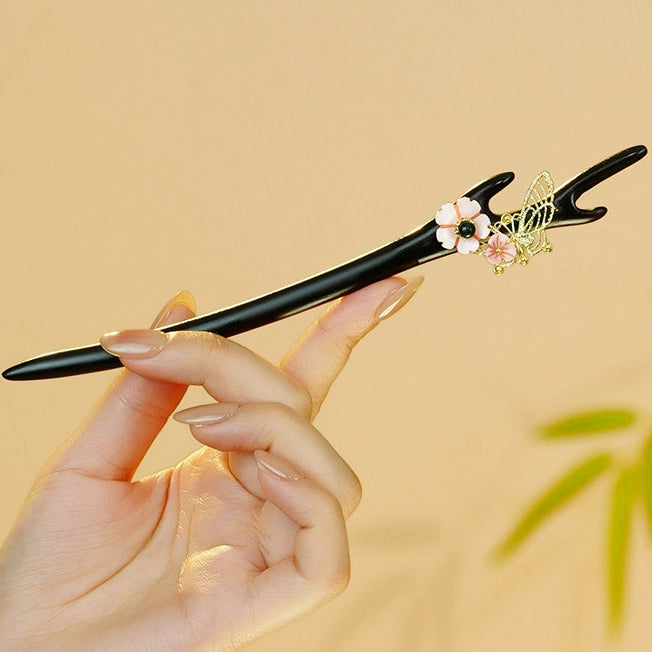 Black and pink hair stick with gold floral accent held in hand