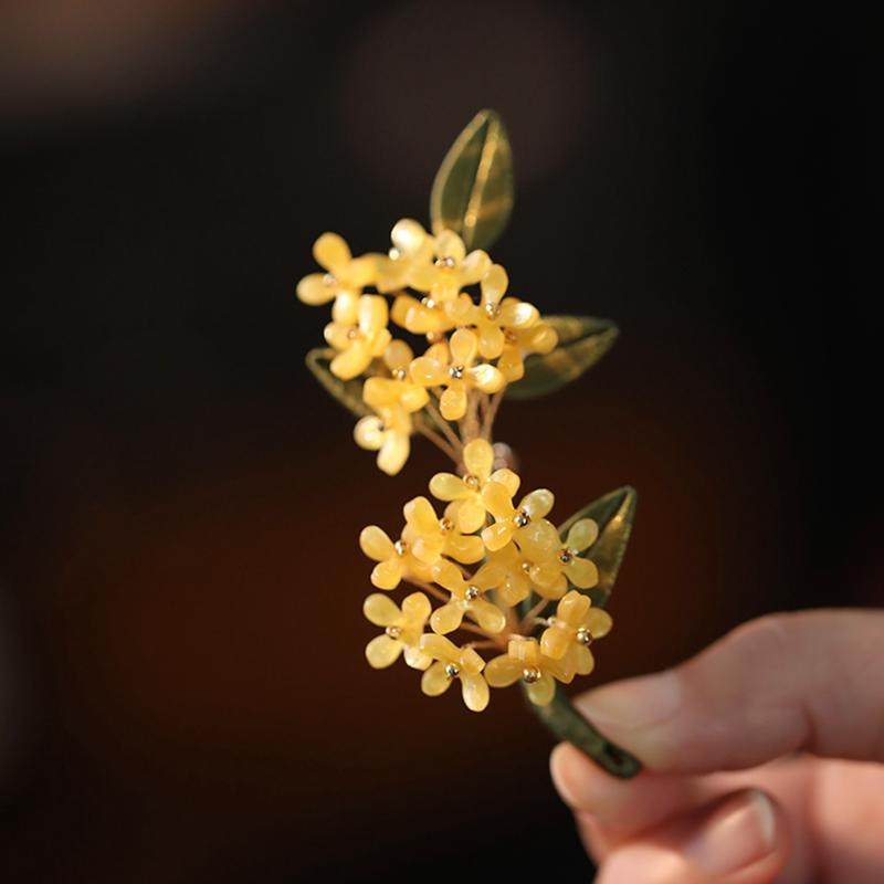 Delicate floral branch brooch with pearlescent accents held in hand