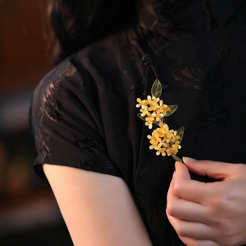 Brooch pinned to cream sweater shoulder, floral motif and soft tones