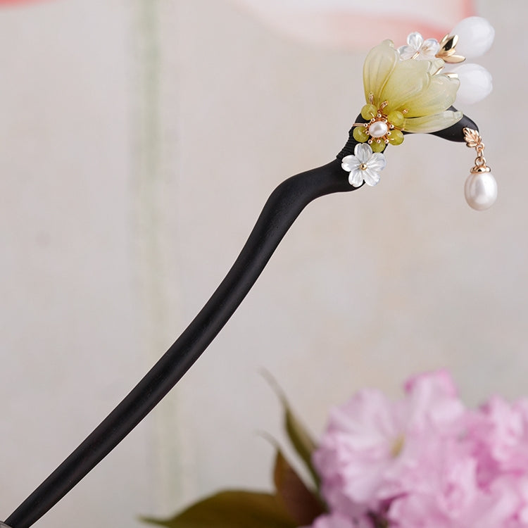 close-up of green magnolia motif set on dark wooden hairpin