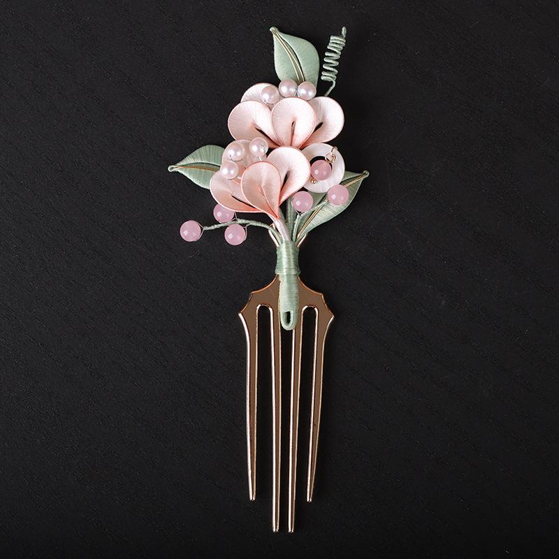 Decorative hair comb with pink flowers and green leaves on a black background