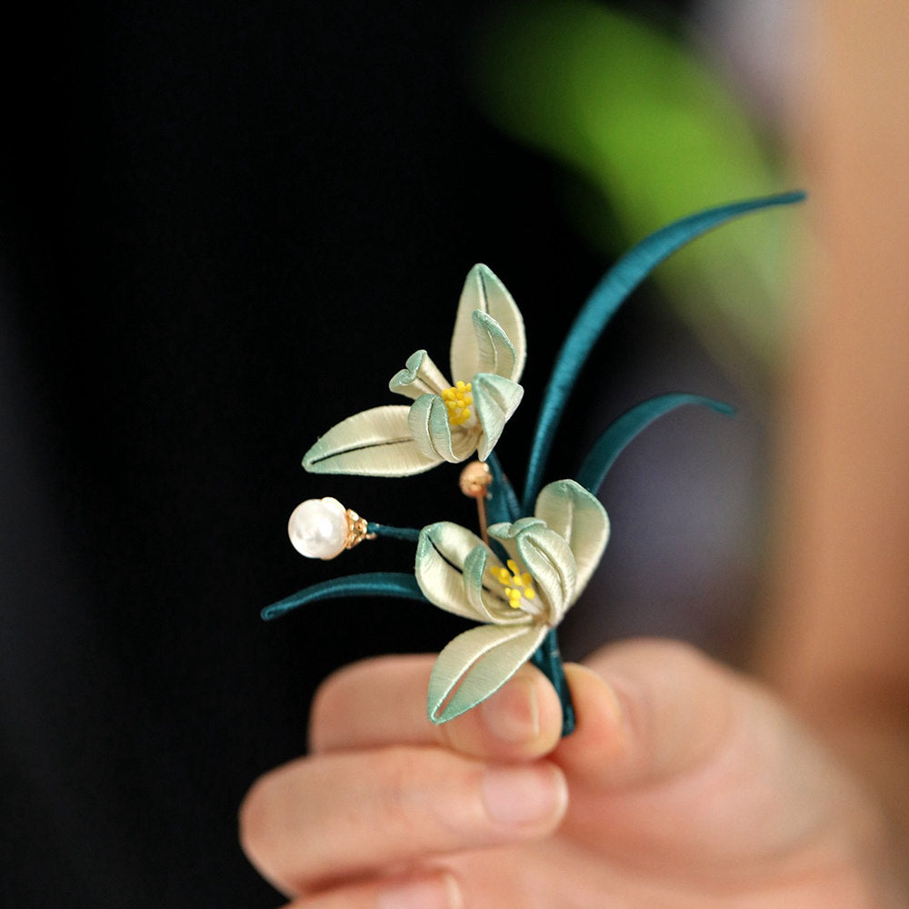 Close-up handheld view showing delicate petals, pearl-like center, and textured metal finish
