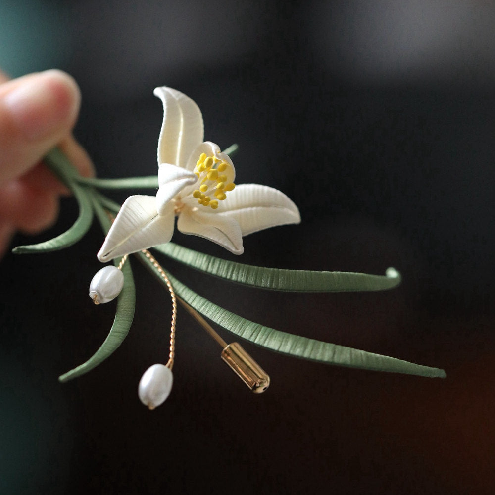 minimal orchid brooch pin styled on a cardigan viewed close up