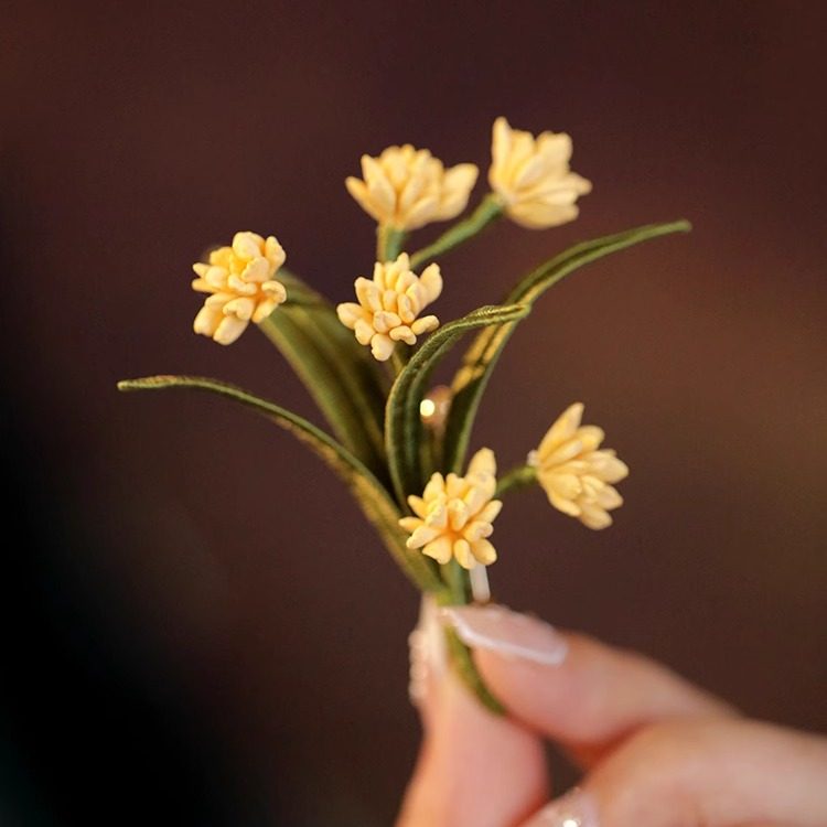 Handheld close-up showing delicate petal detail and tiny pearl-like bead at center