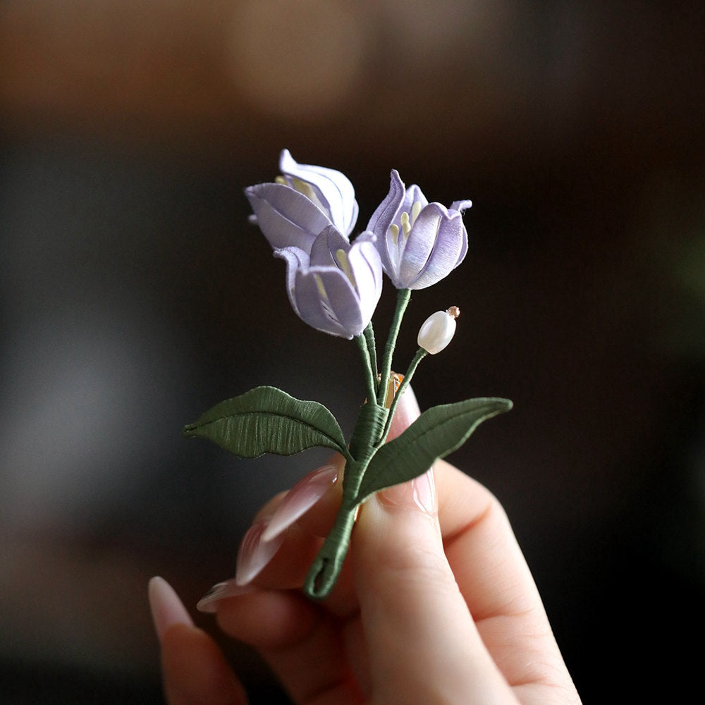 Front view of purple floral pin displaying curved stem and clustered blossoms