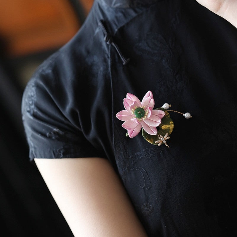 Gold-toned lotus brooch pinned on a red traditional jacket near shoulder