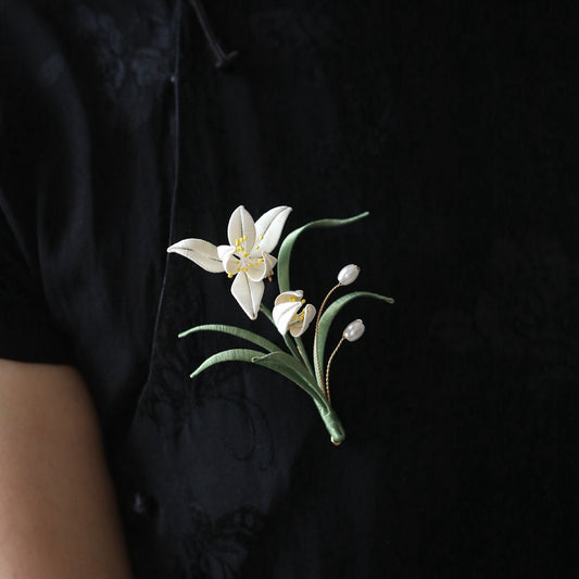 minimal orchid brooch pin styled on a cardigan displayed on fabric