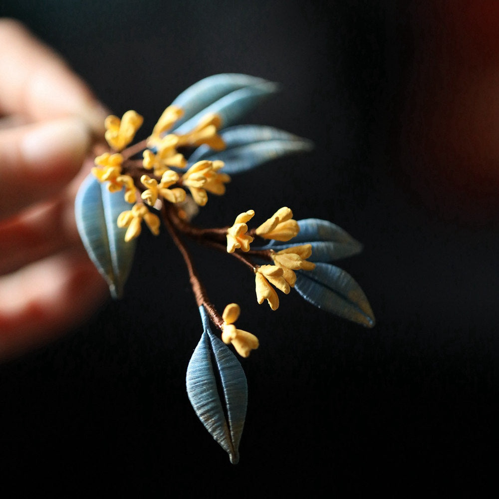 Hand holding floral pin showing textured petals, tiny bead accents and clasp