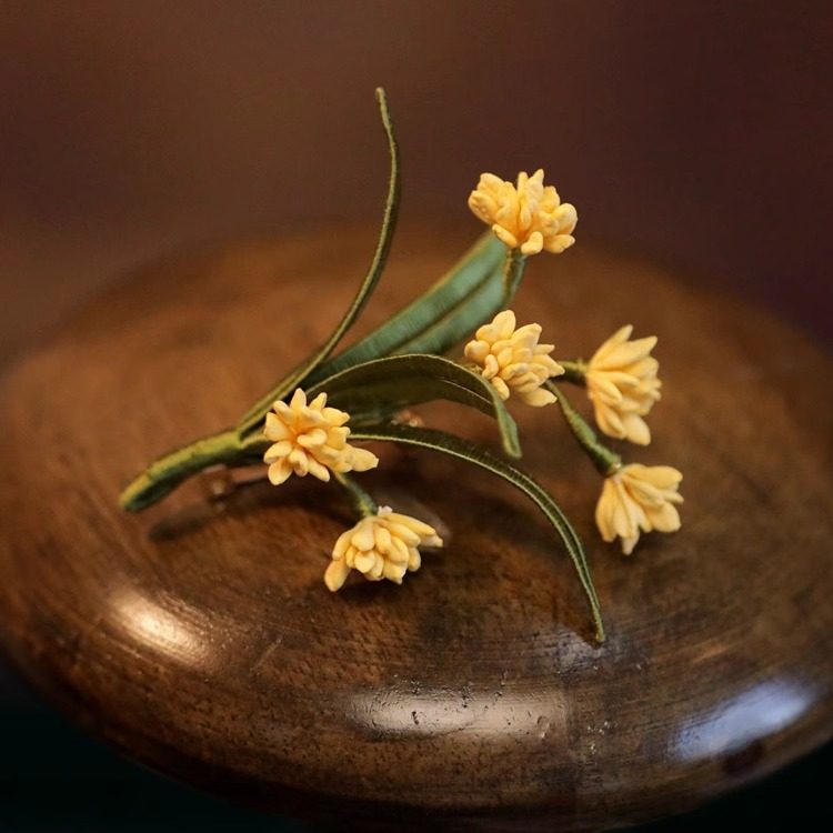 Brooch displayed on wooden stand, suggested styling for coat or collar placement