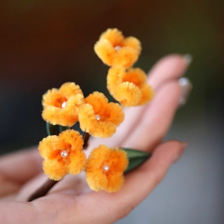 osmanthus-inspired floral brooch on a winter coat styled for an occasion