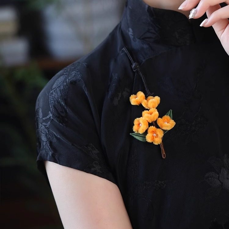 osmanthus-inspired floral brooch on a winter coat viewed close up