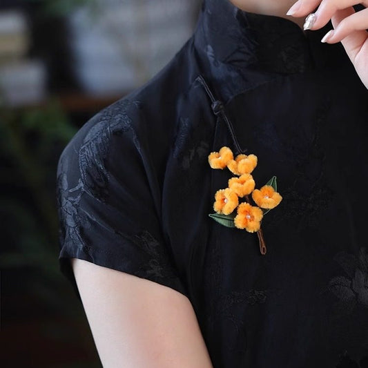 osmanthus-inspired floral brooch on a winter coat viewed close up