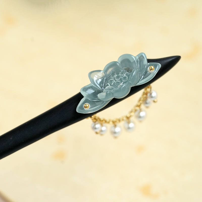 Dark wood hair stick laid flat with lotus ornament and dangling pearl tassel