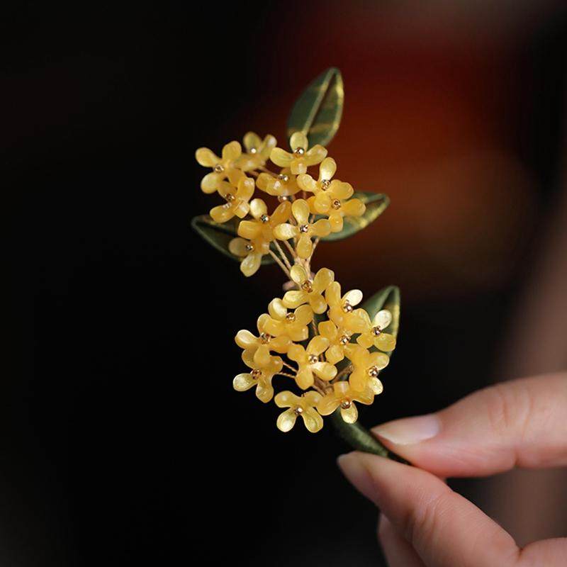 Vintage-inspired branch brooch detail with layered flowers and warm finish