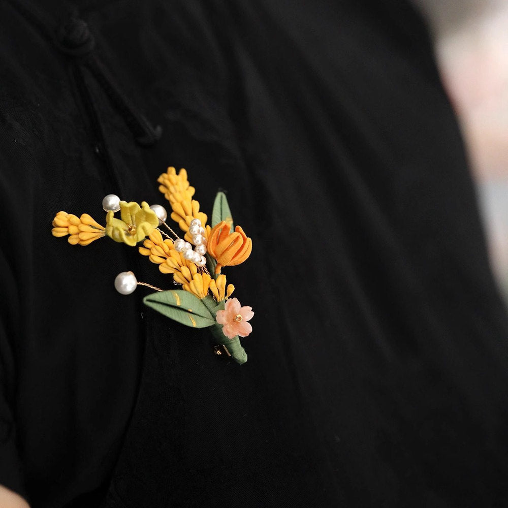 Warm metallic wheat and ivory floral brooch pinned on black outfit lapel