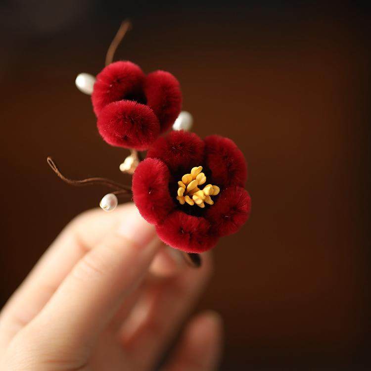 Close-up shows stitched petal texture and beaded center detail on fabric